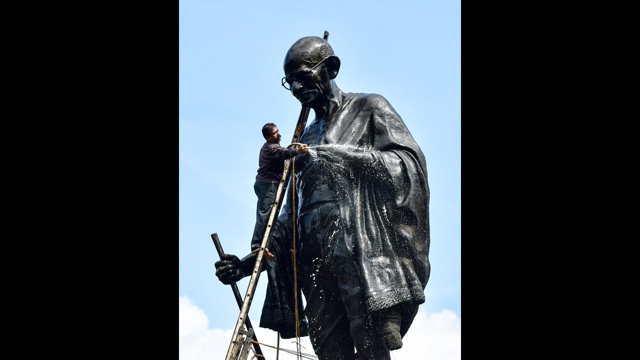 A worker cleans a statue of Mahatma Gandhi ahead of 'Gandhi Jayanti' in Mumbai. Pic/PTI